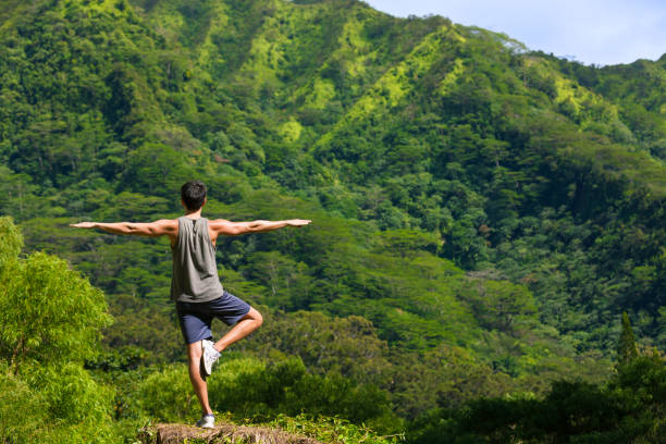Young man doing balancing yoga pose in a beautiful outdoor setting.